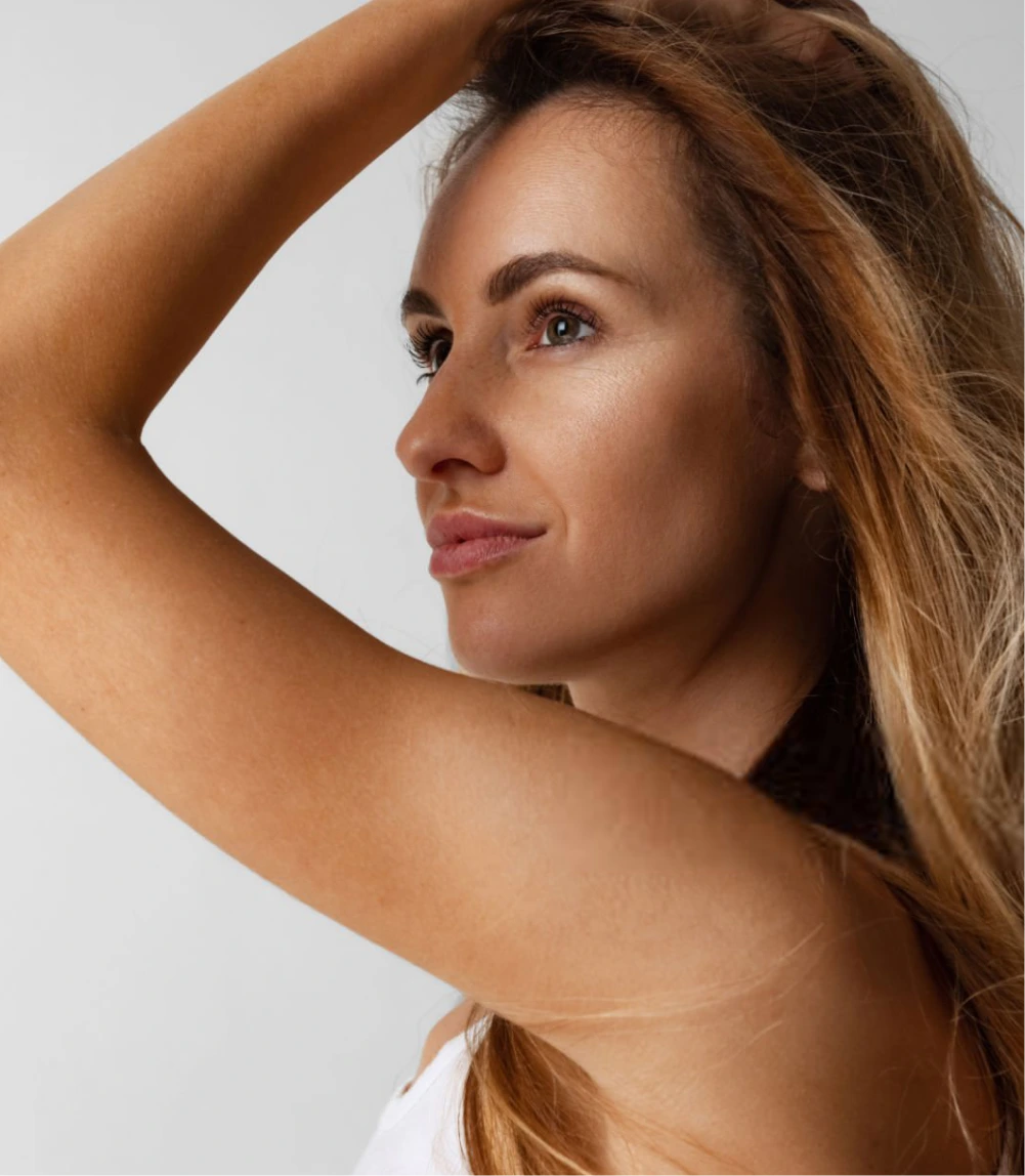 Woman in profile with hand raised, showcasing clear skin and facial features